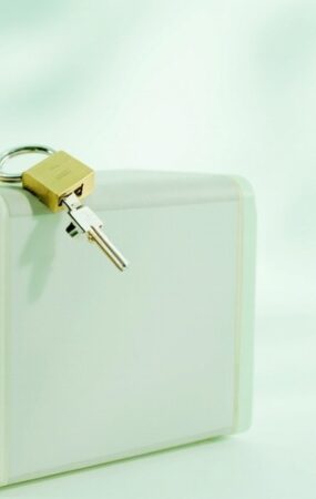 Caja blanca de un servidor con un candado dorado sobre la tapa, sobre fondo claro en tonos verde menta y blanco